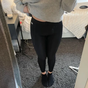Svarta träningstightsfrån Reebok - Säljer ett par svarta träningstights från Reebok. Reebok-logga på sidan.