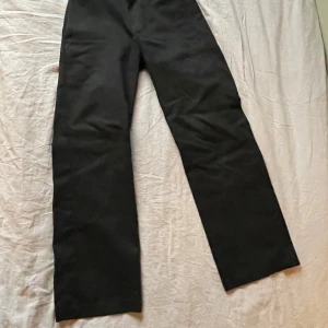 Svarta byxor från Dickies - Snygga svarta byxor från Dickies, modell 874 Original Fit. De har en klassisk design med raka ben och en normal passform. Perfekta för en stilren look.