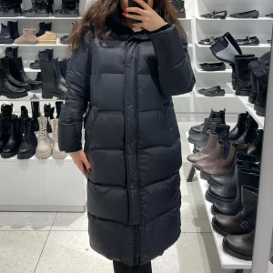 Svart lång dunjacka märke rockandblue 40 nyskick  - Säljer en svart lång dunjacka med dragkedja och knappar. Jackan har långa ärmar och är perfekt för kalla dagar. Den är stilren och enkel att matcha med olika outfits.