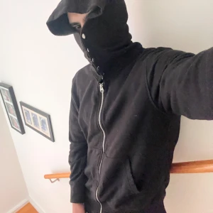 Custom Arket Svart huvtröja med dragkedja - Arket svart huvtröja med dragkedja och knappar längs huvan. Perfekt för en casual look med långa ärmar och praktiska fickor framtill. Huvan ger extra skydd och stil. Passar bra till både jeans och joggers.french terry bomull. Knapparna har jag satt på själv. Litet hål vid kragen.