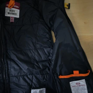 Svart quiltad väst från Parajumpers - Säljer en svart quiltad väst från Parajumpers i storlek XS. Västen har en dragkedja framtill och en broderad logga på bröstet. Perfekt för lager-på-lager under kyligare dagar. Kontakta mig för mer info!