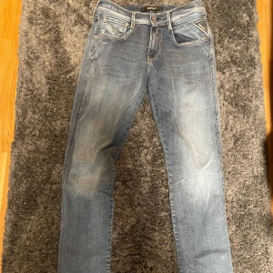 Blå jeans från Replay Anbass - Snygga blå jeans från Replay Anbass med en klassisk femficksdesign och diskreta slitningar. Är perfekta för en avslappnad stil. Märkesdetaljer syns på bakfickorna och i midjan. Nästan helt oanvånda!