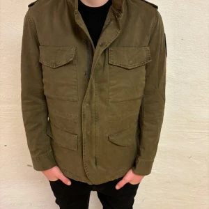 Olivgrön jacka från Zadig & Voltaire - Säljer en olivgrön jacka från Zadig & Voltaire med dragkedja och knappar. Jackan har flera praktiska fickor och en klassisk design. Perfekt för nu när det börjar bli lite varmare. Helt ny tags finns kvar. Jackan är storlek M men passar S också