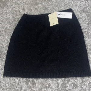 Svart kjol från Gina Tricot - Snygg svart kjol från Gina Tricot i en enkel och stilren design. Kjolen är kort och har en ribbad nederkant som ger en fin detalj. Perfekt för att matcha med olika toppar och accessoarer.