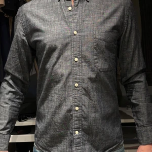 Ruffle & bow. Grå långärmad skjorta M - Snygg grå långärmad skjorta med knappar framtill och en bröstficka. Perfekt för en stilren look. Skjortan har en normal passform och är tillverkad i ett bekvämt material.