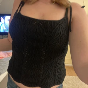 Svart spetslinne från H&M - Säljer ett svart spetslinne från H&M med smala axelband som knyts. Linnet har ett vackert mönster och är perfekt för varma dagar. Passar bra till både jeans och kjol. Hör av dig vid intresse! Aldrig använt.