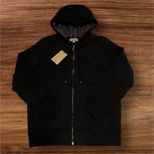 Svart Burberry Kofta Storlek Large  - Säljer en helt ny, svart Burberry kofta i storlek Large. Koftan är aldrig använd och har fortfarande alla taggar kvar. Klassisk och stilren design som passar perfekt både till vardags och till finare tillfällen. 