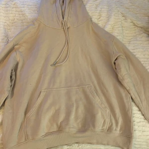 Beige hoodie från H&M - Säljer en stilren beige hoodie från H&M. Den har en klassisk design med känguruficka och justerbar huva. Perfekt för en avslappnad look.
