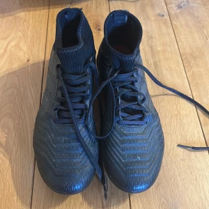 Svarta fotbollsskor Adidas Predator - Säljer ett par svarta fotbollsskor för mjukt underlag. Använda några gånger men nu har jag tyvärr växt ur dem.