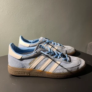 Adidas Spezial i ljusblå mocka -  Adidas  Handball Spezial sneakers i ljusblå mocka med vita detaljer och klassiska tre ränder. Skorna har en brun sula och snörning i matchande ljusblå färg. Perfekta för en sportig och stilren look. Kan rengöras mer vid köp.  Nypris 1349kr, mitt pris 599kr. Priset är inte hugget i sten 🪨vid snabb affär. Hör av er vid minsta funderingar. Mvh Sigge🥂🤙
