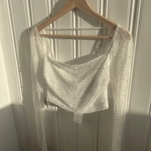 Vit glittrig topp med långa ärmar - Säljer en elegant vit topp från Gina tricot med pärlor och glittriga detaljer. Toppen har långa ärmar och en vacker, skimrande yta som fångar ljuset. Perfekt för speciella tillfällen när du vill glänsa lite extra. 💫Perfekt till vardag, fest och studenten💖☺️❤️🎀prislapp kvar på (499 orginal pris) passar tyvärr inte mig längre så hoppas den får ett bättre hem🥰