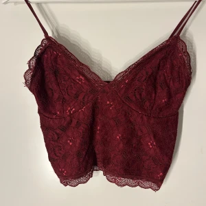 Vinröd spetslinne från BikBok - Säljer ett snyggt vinrött spetslinne från BikBok. Linnet har smala axelband och vacker spetsdetalj runt kanterna. Perfekt för en stilren look. 💖