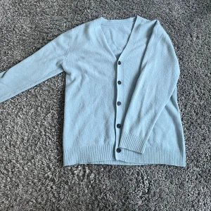 Cashmir kofta i Ljusblå  - Säljer en stilren ljusblå kofta med knappar framtill. Den är i 100% Kashmir märker är oklar där av priset i extremt bra skick ! Passar S/M