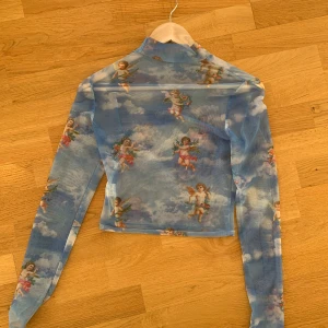 Topp med änglar - Så fin meshtopp med gulligt tryck av änglar. Har sytt igen hål under armarna, inhet som syns men skickar självklart bild vid önskemål 🩷vet tyvärr inte märket! 