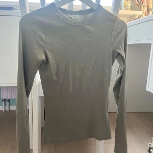 Grön ribbad långärmad topp från H&M - Säljer en stilren grön ribbad långärmad topp från H&M. Perfekt för lager-på-lager eller som den är. Enkel och mångsidig design som passar till det mesta. 🌿