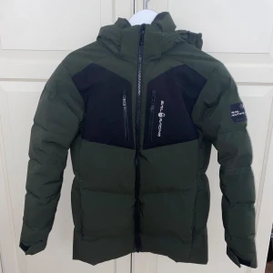 Sail racing Grön dunjacka  - Snygg grön dunjacka från Sail Racing som passar väldigt bra för vinter och höst. Jackan har inga skador eller repor och har bara och den användes bara i en vinter. Storlek 160 men passar även 170. Pris kan diskuteras.