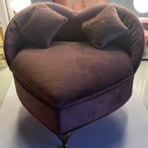 Smyckeskrin i form av en soffa - Charmigt smyckeskrin format som en liten soffa i brun sammet. Skrinet har en hjärtformad design med två små kuddar och en spegel inuti locket. Perfekt för att förvara ringar och andra små smycken.