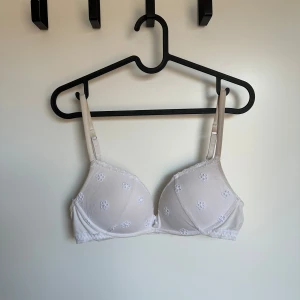 Vit broderad Intimissimi BH - Säljer en söt vit bh med broderade blommor. Den har justerbara axelband och en mjuk push-up kupa för extra komfort. Perfekt för vardagsbruk eller speciella tillfällen. 75C