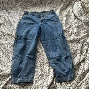 Blå jeansbyxor - Säljer ett par klassiska blå jeansbyxor med normal passform. De har en dragkedja och knapp framtill. Perfekta för en avslappnad stil.