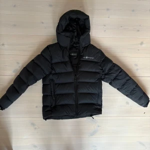 Svart dunjacka från Sail Racing - Säljer en svart dunjacka från Sail Racing i storlek M. Relativt tjock, väldigt skön. Sparsamt använd, mycket bra skick. Passar för ca 175-185. Nypris 4500:-