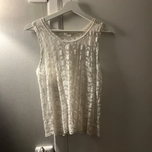 Vit spetslinne - Säljer ett superfint vitt spetslinne i storlek 170. Perfekt för sommardagar eller som ett lager under en kavaj. Det är ärmlöst och har ett vackert blommigt mönster. Passar både till vardags och festliga tillfällen!