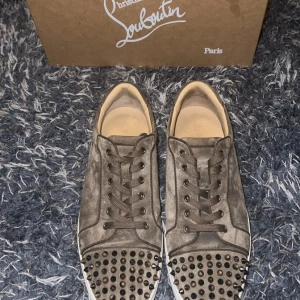    Christian Louboutin - Säljer ett par brun/beuge sneakers från Christian Louboutin i mycket bra skick. Skorna är i mocka med coola nitar på tån och sidorna. De har den klassiska röda sulan som är typisk för märket. Strl 44 sitter som 43 allt OG tillkommer, skorna är köpta från mythresa! 