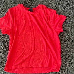 Röd ribbad t-shirt - Säljer en snygg röd ribbad t-shirt i mycket bra skick. Den har en normal passform och korta ärmar, perfekt för sommardagar.  Passar både till vardags och festligare tillfällen. Ett måste i garderoben! 🔥 Är liten i storleken passar mig som brukar ha S