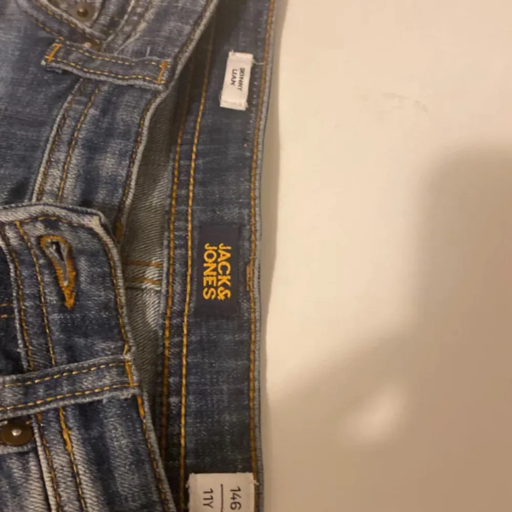 Säljer ett par snygga blå jeans från Jack & Jones i storlek 146. De har en slim passform och är i bra skick med coola slitningar på framsidan. Perfekta för både vardag och fest! 🕺. Farkut & Housut.