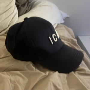 Mörkblå  keps från Dsquared2 - Säljer en svart keps från Dsquared2 med texten 'ICON' broderad framtill. Kepsen har en justerbar rem baktill och är i mycket bra skick. Perfekt för att ge din outfit en cool touch! 🖤