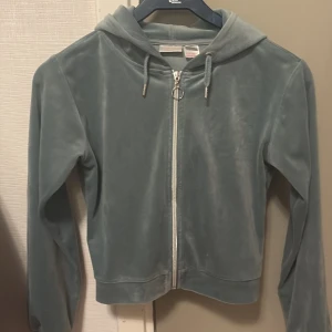 Skogs grön hoodie från Gina Tricot - Mysig hoodie från Gina Tricot i mjukt material. Den har en dragkedja framtill och en praktisk huva. Perfekt för kyliga dagar eller som ett extra lager. Passar bra till både vardag och avslappnade tillfällen.