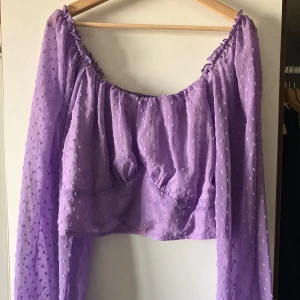 Topp - Lila croppad topp i polyester. Förstärkningstyg på plaggets framsida. 