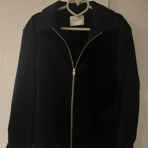 Svart jacka från These Glory Days - Säljer en stilren svart overshirt från These Glory Days i storlek L. Jackan har en dragkedja framtill och är långärmad. Perfekt för höst och vår med sitt mjuka material som ger en skön känsla. Passar både till vardags och lite finare tillfällen. 🖤