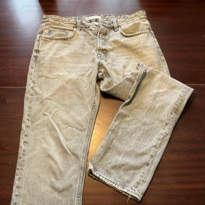 Gråa jeans från Zara - Säljer ett par grå jeans från Zara i bra skick. Storlek 42. De har en klassisk femficksdesign och är tillverkade i ett slitstarkt material. Passformen är relaxed. Inga fläckar eller hål, dock kanske lite slitet nere vid fötterna och fickorna.  