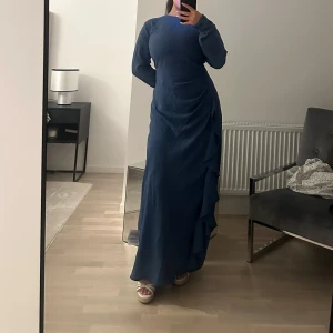 Blå långklänning - Säljer en elegant blå långklänning i ett mjukt och bekvämt material. Klänningen har en stilren design med långa ärmar och en figurnära passform som ger en smickrande siluett. Perfekt för höst- och vinterevenemang. Passar både till vardags och festligare tillfällen.
