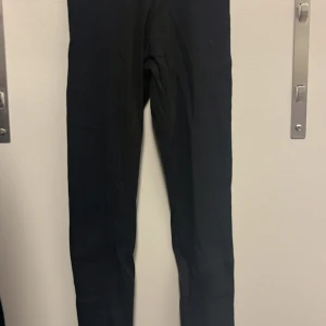 Svarta ribbade leggings från H&M Divided - Säljer ett par svarta ribbade leggings från H&M Divided i storlek XS. De är tillverkade av 95% bomull och 5% elastan, vilket gör dem både bekväma och stretchiga. Perfekta för en avslappnad stil eller som basplagg i garderoben. Använda men i bra skick.