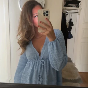 Ljusblå tie front top - Säljer denna otroligt fina toppen från gina tricot, den är öppen fram och man knyter där fram, väldigt vårig och sommrig😍🌸🌺det är storlek xxs men passar hur bra som helst på mig som är xs/s