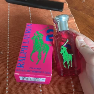 Ralph Lauren parfym för kvinnor - Säljer en elegant parfym från Ralph Lauren för kvinnor. Flaskan är rosa med en silverfärgad kork och har en grön logotyp av en polospelare. Förpackningen är också rosa med blå och gröna detaljer. Perfekt för den som älskar en fräsch och stilren doft. Fick som present men gillar inte doften och är som ny💘