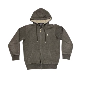 Grå hoodie från Ralph Lauren - Säljer en stilren grå hoodie från Ralph Lauren med dragkedja och broderad logga på bröstet. Hoodien har en mysig fodrad insida och långa ärmar. Perfekt för kyliga dagar!  Lite noppor men inget som spelar roll alls. Hör av er vid frågor!