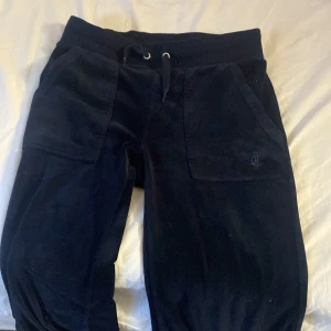 Svarta mjukisbyxor från Juicy Couture - Snygga svarta mjukisbyxor från Juicy Couture i storlek XXS. Byxorna har en bekväm passform med snörning i midjan och praktiska fickor både fram och bak. Perfekta för en avslappnad stil.