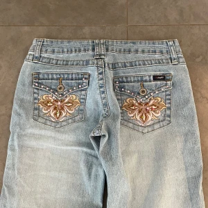 Lågmidjade bootcut jeans med unika fickor - (5) Världens snyggaste ljusblåa lågmidjade jeans med fina fickor och stretch i! Midjemått rakt över: 34cm, innerbenslängd: 80 cm💞