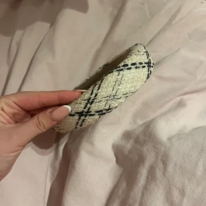 Beige och svart diadem - Snyggt diadem i beige med svart rutigt mönster. Perfekt accessoar för att ge din outfit en stilfull touch. Passar bra för både vardag och speciella tillfällen.
