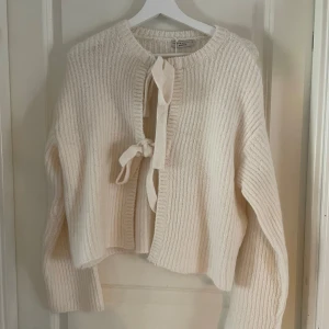 Offwhite stickad kofta från Gina Tricot - Säljer en mysig offwhite stickad kofta från Gina Tricot. Koftan har långa ärmar och knytband framtill som ger en fin detalj. Perfekt för kyligare dagar och lätt att matcha med olika outfits. Ny med prislapp och inga defekter💘💘 