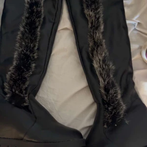 Svarta stövlar med fuskpäls - Snygga svarta stövlar med fuskpälsdetaljer längs skaftet. Perfekta för kalla dagar med en stilren look. De har en robust sula som ger bra grepp.