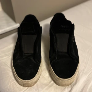 Svarta sneakers från Axel Arigato - Snygga svarta sneakers från Axel Arigato med en stilren design. Skorna har en vit sula och är tillverkade i mocka. Perfekta för en avslappnad stil.