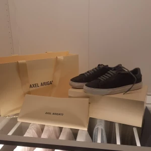 Axel Arigato Clean 90 Suede Sneakers - Snygga Axel Arigato Clean 90 sneakers i mörkgrå mocka med vit sula. Dessa sneakers har en stilren design med snörning och är perfekta för en modern look. Kommer i originalförpackning.nypris är 2400 pris kan diskuteras