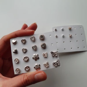 Set med guldfärgade örhängen - Säljer ett set med 12 olika guldfärgade örhängen i olika former som hjärtan, blommor, fjärilar och pärlor. De har aldrig använts mer än att de har testats och säljs alla tillsammans. Skriv vid frågor.