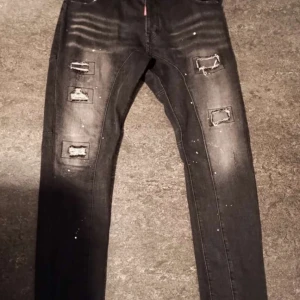 Svarta jeans med slitningar från Dsquared2 - Snygga svarta jeans från Dsquared2 med coola slitningar och en slim passform. Tillverkade i Italien, dessa jeans har en modern look med slitna detaljer på benen. Perfekta för en trendig stil.