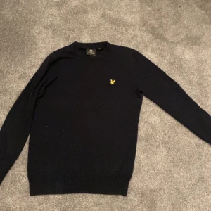 Marin blå tröja från Lyle & Scott - Snygg marinblå stickad crewneck från Lyle & Scott. Väldigt skönt material och bra passform. Ny pris är 900 och den är i bra skick. Passar dig som är runt 170. 