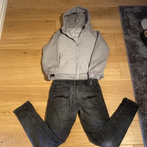 Grå cardigan  - Säljer en stilren grå quiltad jacka med huva. Jackan har dragkedja framtill och är perfekt för kyligare dagar. Den är långärmad och har en modern look. Storleken är S men passar bra på M också. Den är helt oanvänd