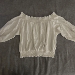 Vit offshoulder topp från Sinsay - Säljer en söt vit offshoulder topp från Sinsay. Toppen har en elastisk kant vid axlar och midja som ger en fin passform. Perfekt för varma dagar!